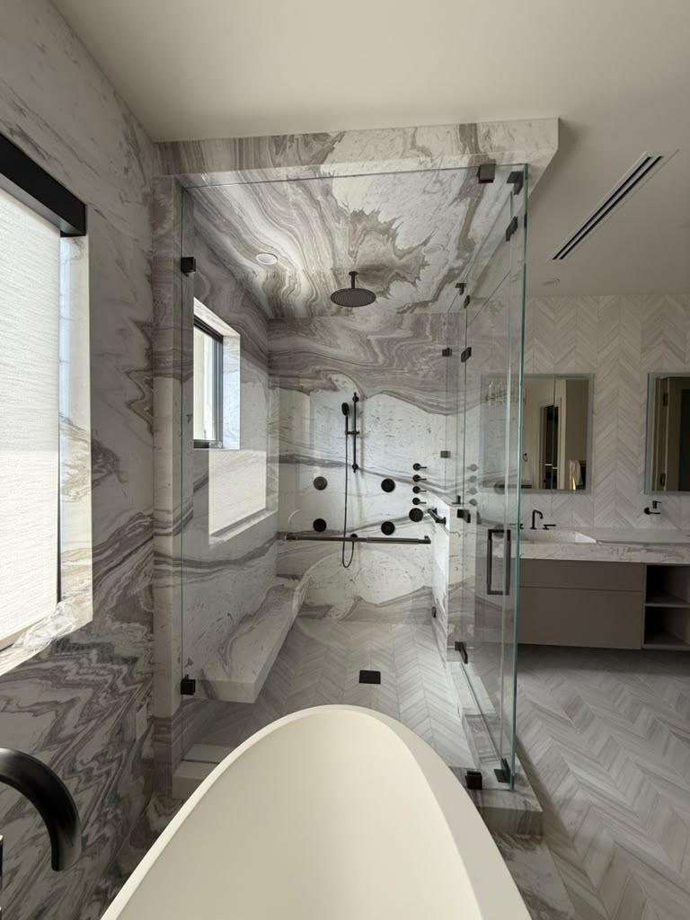 Finished frameless shower enclosure with dark hardware and marble walls